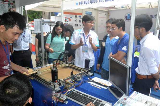 Sinh viên Trường ĐH Bách khoa (ĐH Quốc gia TP.HCM) trình bày về cơ chế hoạt động của máy khắc laser với khách tham quan - Ảnh: Quang Phương