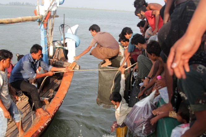 Người di cư giúp lai dắt tàu chở người di cư vào bờ gần Aceh - Ảnh: AFP