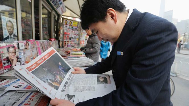 Người dân Trung Quốc đọc báo giấy tại một quầy báo ven đường ở Bắc Kinh - Ảnh: Reuters