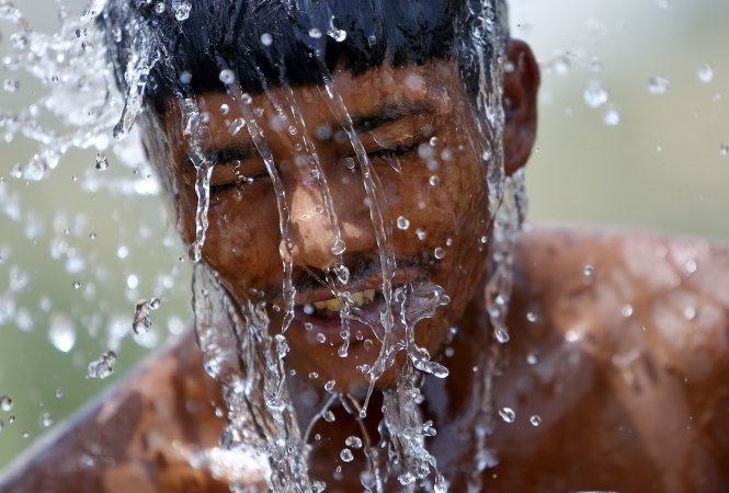 Một công nhân ở Gurgaon (Ấn Độ) tranh thủ giải nhiệt tại trạm bơm nước - Ảnh: Reuters