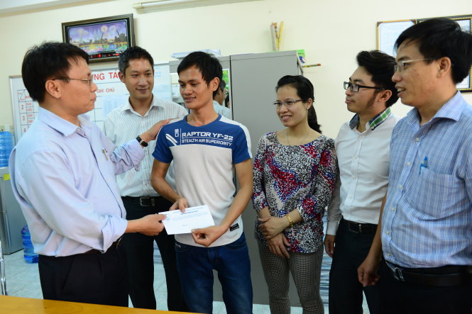 Tiến sĩ Nguyễn Quốc Hiển (trái) trao tiền do các giảng viên của trường quyên góp cho Nam - Ảnh: Q.Định