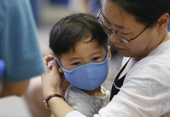 Một hành khách đeo khẩu trang cho con phòng lây nhiễm MERS tại sân bay quốc tế Incheon ngày 14-6 - Ảnh: Reuters