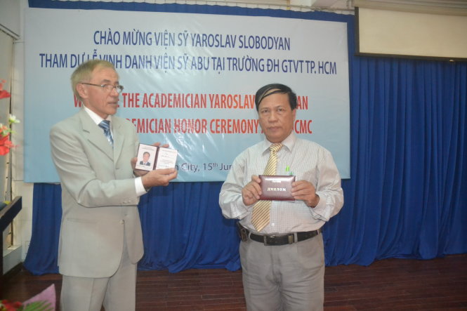 Ông Trần Đức Chính (phải) với chứng nhận viện sĩ Viện ABU và tấm thẻ viện sĩ ABU được đại diện Viện ABU giới thiệu tại buổi lễ - Ảnh: Q.Phương
