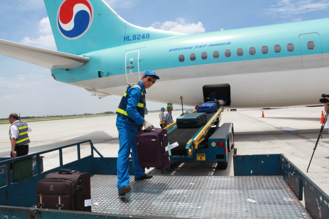 Nhân viên bốc xếp vận chuyển hành lý ký gửi tại sân bay Nội Bài -  Ảnh: Tuấn Phùng
