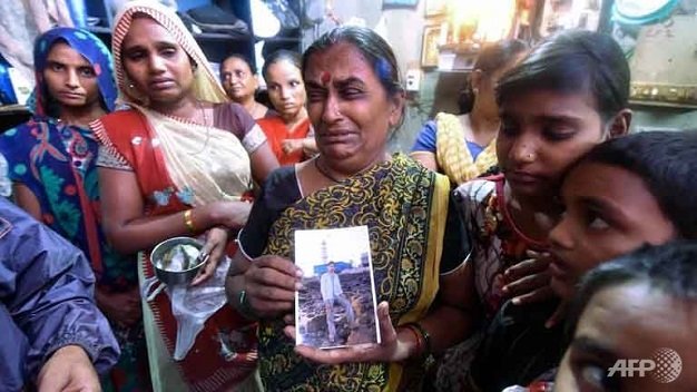 Gia đình cầm ảnh một nạn nhân qua đời vì ngộ độc rượu ở Mumbai Ảnh: AFP