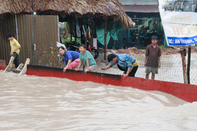 Người dân trên quốc lộ 13, đoạn giáp giữa TP Thủ Dầu Một và thị xã Thuận An (Bình Dương) khốn khổ vì đường ngập sau mưa lớn chiều tối 21-6   Ảnh: XUÂN AN