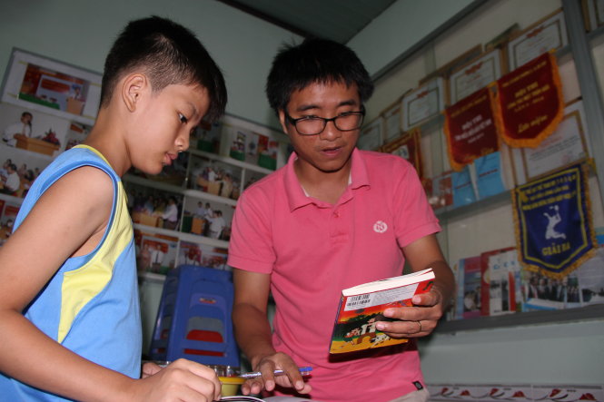 Anh Trí đang cho Nhật Huy (học sinh lớp 5 Trường tiểu học Nguyễn Viết Xuân) mượn sách về nhà đọc - Ảnh: Phước Tuần