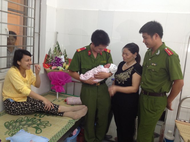 Thượng sĩ Đoàn Thanh Tùng (thứ hai từ trái sang) và thiếu úy Nguyễn Văn Tiệp (bìa phải) cùng gia đình cháu bé - Ảnh: Anh Quang