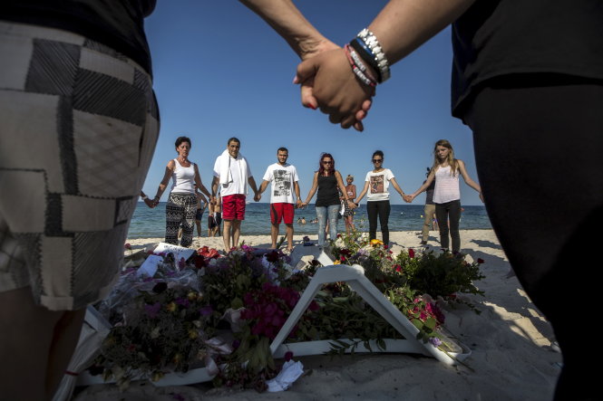 Người dân ở bãi biển tại Sousse, Tunisia nắm tay cầu nguyện cho các nạn nhân bị khủng bố - Ảnh: Reuters