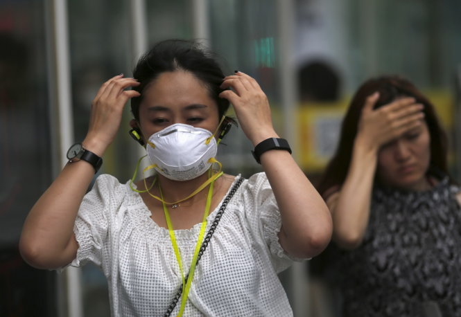 Phụ nữ Trung Quốc đeo khẩu trang chống ô nhiễm ở Bắc Kinh  -  Ảnh: Reuters