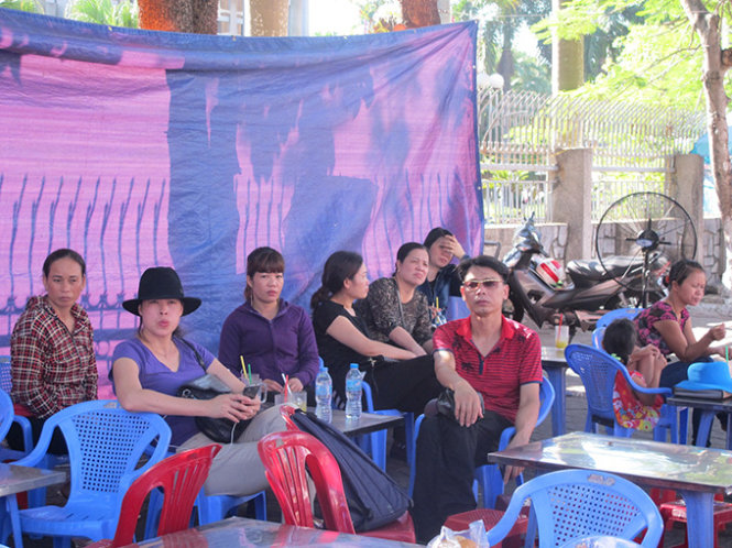 Các bậc phụ huynh ngồi ở quán nước bên đường trước cổng đại học Hàng Hải trốn nắng đợi con thi - Ảnh: Thân Hoàng