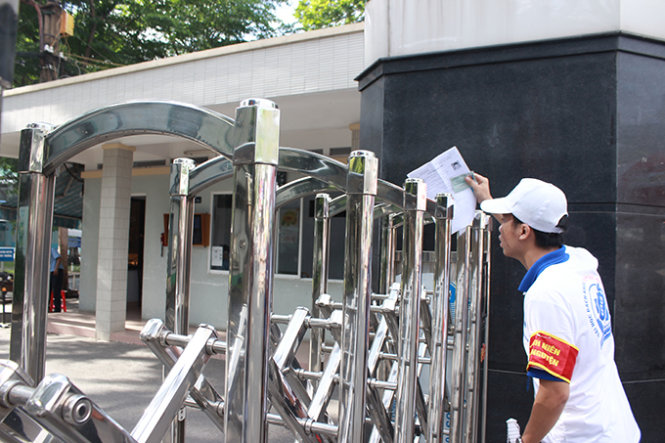 Tình nguyện viên đưa giấy tờ của Cương qua cổng Trường ĐH Bách khoa lúc 7g50 - Ảnh: Phương Nguyễn