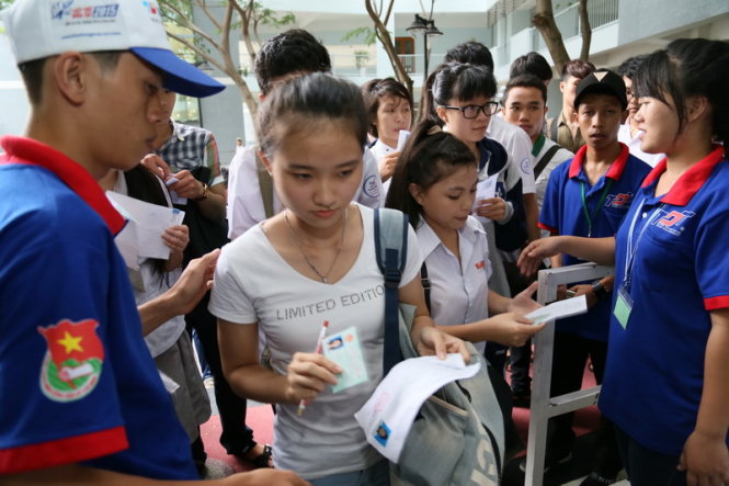 Sinh viên tình nguyện  đang kiểm tra thẻ dự thi của thí sinh trước khi vào khu vực thi môn anh văn chiều 1/7 tại HĐT trường ĐH Tôn Đức Thắng - Ảnh: Như Hùng
