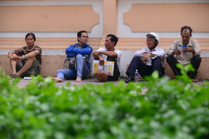 Một nhóm phụ huynh ngồi bệt xuống đất chờ con thi môn vật lý tại Trường THPT chuyên Lê Hồng Phong, TP.HCM trưa 2-7 Ảnh: QUANG ĐỊNH