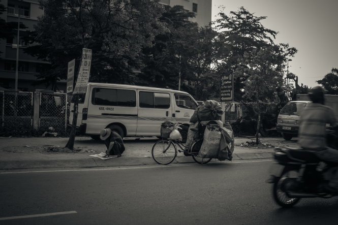 người đàn ông này say sưa đọc tờ báo mà ông nhặt được trong đống giấy vụn do mình thu mua được