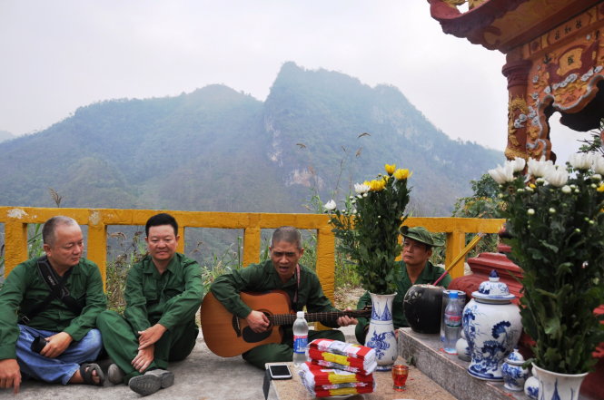 Nhạc sĩ Trương Quý Hải ôm đàn hát cùng các cựu chiến binh dưới chân đài hương, phía sau lưng là các điểm cao 685 (phải), 772 (trái) - Ảnh: NGỌC QUANG
