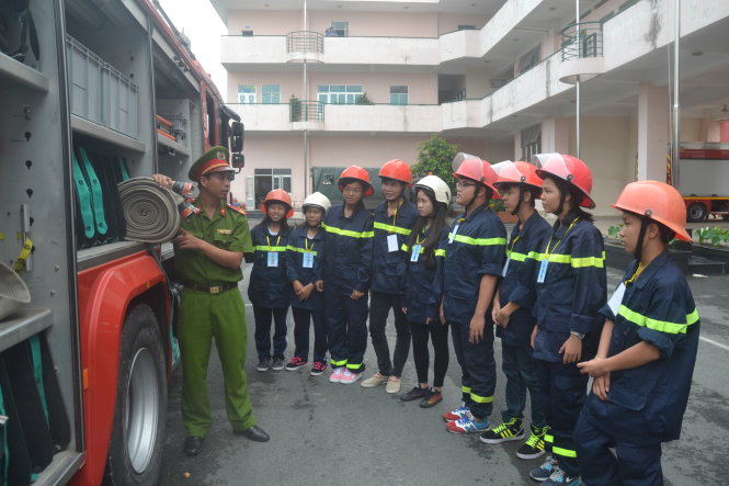 Anh Nguyễn Đình Vinh (trái), tiểu đội trưởng đội chữa cháy chuyên nghiệp Phòng Cảnh sát PCCC quận 2, hướng dẫn các bạn thanh thiếu niên sử dụng phương tiện chữa cháy Ảnh: QUANG PHƯƠNG