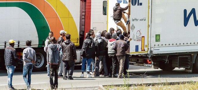 Người nhập cư tranh thủ xe tải bị kẹt tại cửa ngõ hầm eo biển Manche từ Pháp qua Anh để trèo vào xe ẩn nấp - Ảnh: AFP