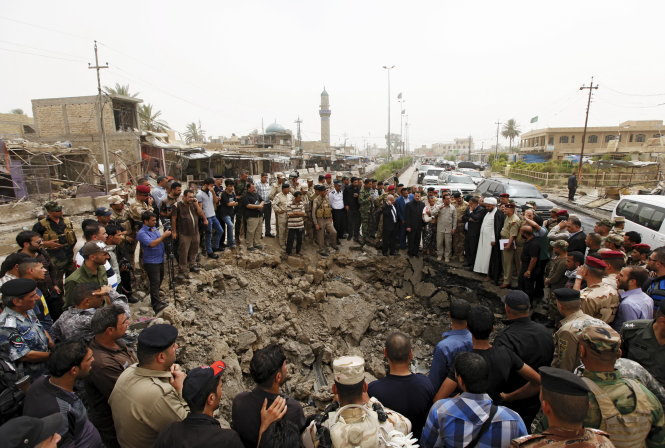 Nhân viên an ninh và người dân Iraq đứng xung quanh cái hố do quả bom 3 tấn tạo ra - Ảnh: Reuters