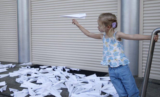 Bé gái tung máy bay giấy tự làm bên ngoài đại sứ quán Hà Lan tại Kiev khi mọi người tập trung kỷ niệm 1 năm xảy ra vụ máy bay MH17 bị bắn rơi - Ảnh: Reuters