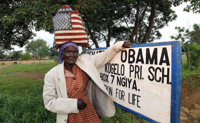 Người phụ nữ đi chợ với chiếc túi in hình cờ Mỹ, chụp ảnh cạnh ngôi nhà của gia đình ông Barack Obama ở làng Nyangoma - Ảnh: Reuters