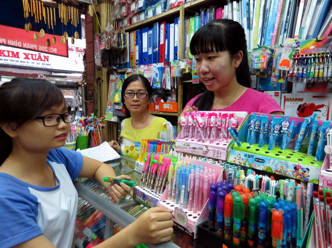 Phụ huynh và học sinh lựa chọn tập vở và dụng cụ học tập cho năm học mới - Ảnh: T.Đạm