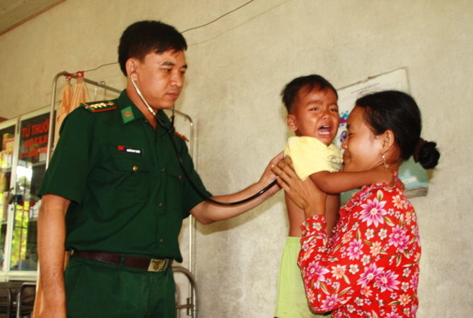 Thượng úy Nguyễn Duy Thuần khám bệnh cho bé Phích Cuông Kia, con trai chị Xôm Phích ở xã Crua, huyện Svay Chrum, tỉnh Svay Rieng (Campuchia) Ảnh: SƠN LÂM