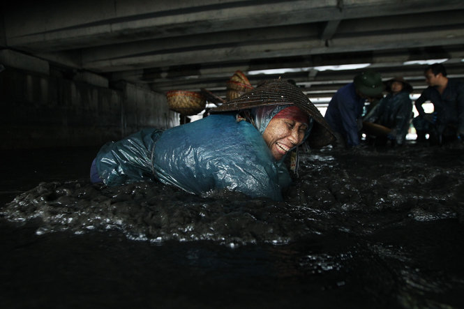 Bà Yến một người dân tại Thành Phố Cẩm Phả đang đầm mình xuống dòng nước đen kịt để vớt than, mỗi ngày công làm việc cả ngày  bà thu về được 4 đến 5 tạ than tương ứng khoảng 400.000 - 500.000đ - Ảnh: Nguyễn Khánh