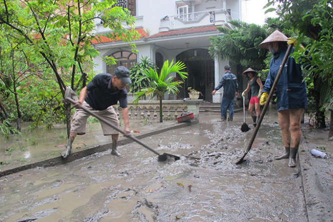 Người dân tiếp tục dọn dẹp bùn đất tràn vào nhà sau khi nước lũ rút đi - Ảnh: Thân Hoàng