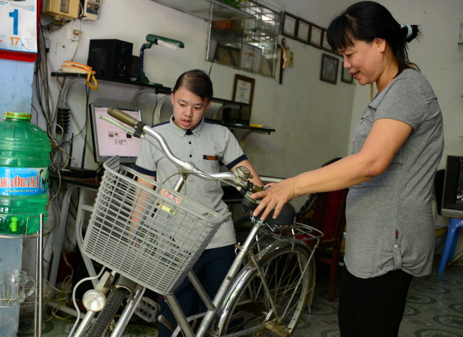 Bà Nguyễn Thị Thu Hương và con trai Đỗ Minh Hội bên cạnh một trong những chiếc xe được bà vận động quyên góp để chuyển cho các học sinh nghèo (ảnh chụp ngày 1-8-2015) - Ảnh: T.T.D.