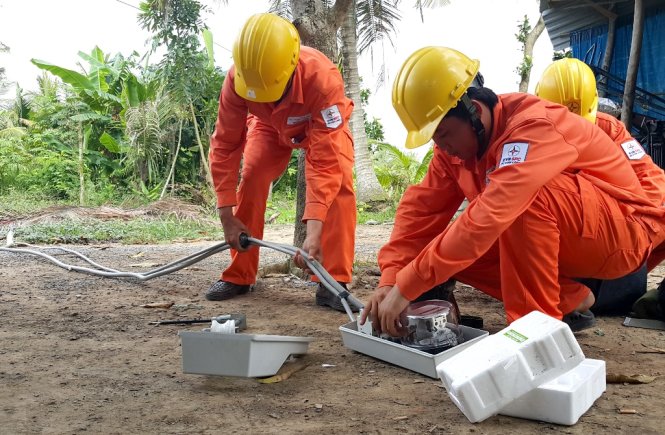 Nhân viên điện lực lắp đặt hệ thống điện cho hộ gia đình ở xã Trung Hiếu, huyện Vũng Liêm, Vĩnh Long - Ảnh: Thúy Hằng