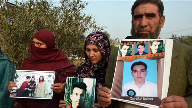 Bố mẹ của những học sinh thiệt mạng trong vụ thảm sát cầm di ảnh các nạn nhân bên ngoài khuôn viên trường Peshawa - Ảnh: AFP