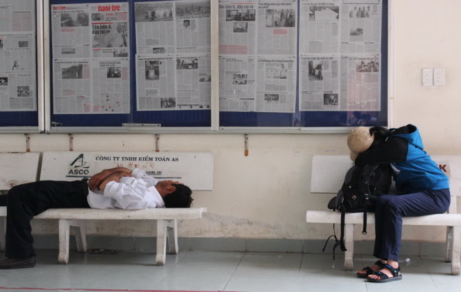 Một phụ huynh quá mệt mỏi đã ngã lưng ngay tại hàng ghế hành lang tại Trường ĐH Kinh tế TP.HCM - Ảnh: Thục Trinh