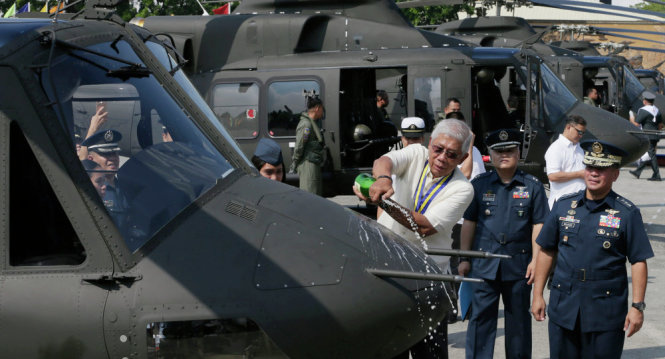 Bộ trưởng Quốc phòng Philippines đổ rượu Champagne lên một chiếc trực thăng Bell-412EP trong lễ biên chế 10 chiếc cùng loại. Ảnh: AP