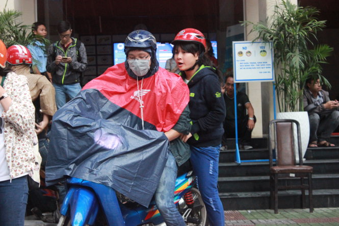 Thí sinh Nguyễn Minh Nguyệt và anh trai đội mưa đi từ Trường ĐH Kinh tế ra Bưu điện TP.HCM nộp hồ sơ cuối ngày 20-8 - Ảnh: Hồng Nguyên
