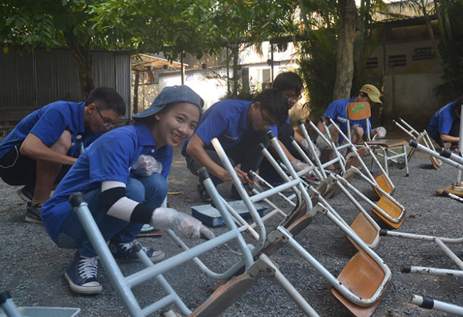 Các tình nguyện viên sơn lại bàn ghế Trường tiểu học Đông An - Ảnh: Quang Phương