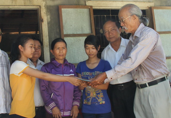 Ông Thành (bìa phải), chủ tịch hội đồng tộc Trịnh Quảng Ngãi, trao tiền hỗ trợ cho hai cô gái họ Trịnh vượt khó đến trường - Ảnh: Trần Mai