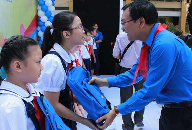 Phó bí thư thường trực Thành đoàn TP.HCM Lâm Đình Thắng (phải) trao cặp và dụng cụ học tập cho các em học sinh nghèo chuẩn bị vào năm học mới - Ảnh:Q.L.