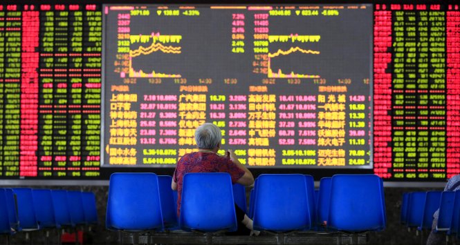Một nhà đầu tư ngồi trước bảng điện tử tại một công ty môi giới chứng khoán ở Thượng Hải - Ảnh: Reuters