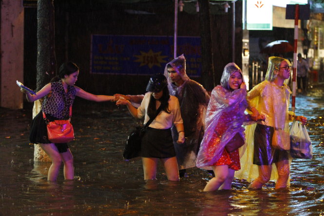 Một nhóm bạn trẻ phải lội qua đoạn ngập lớn tại đường Liễu Giai - Ảnh: Nam Trần