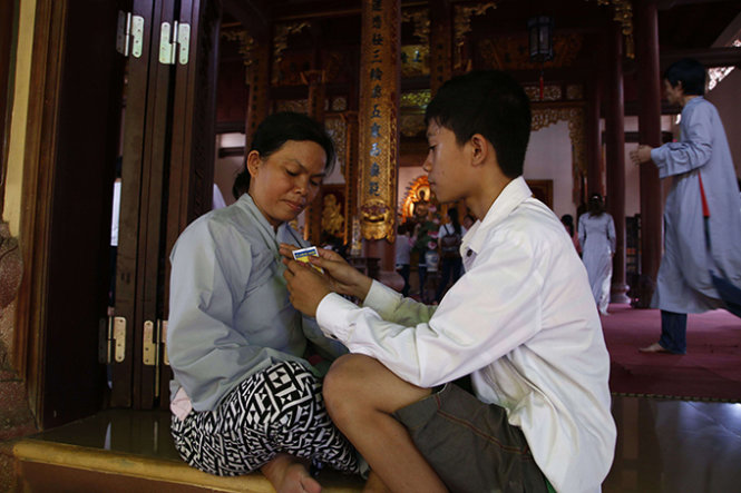 Em Lê Văn Thiện (TP. Huế) đang giúp mẹ cài bông hoa hồng trắng lên áo trong ngày lễ Vu lan- Ảnh: Ngọc Dương