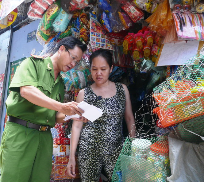 Tổ công tác hướng dẫn chị Nguyễn Thị Kim Phương làm mới CMND tại tiệm tạp hóa của chị Ảnh: SƠN BÌNH