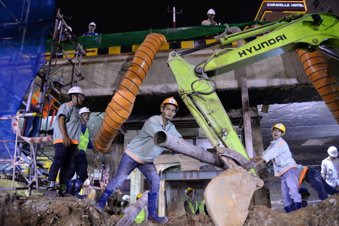 Các công nhân dưới lòng đất di chuyển ống bơm bêtông vào vị trí đổ nền cho tầng hầm đầu tiên của nhà ga ngầm trước Nhà hát TP