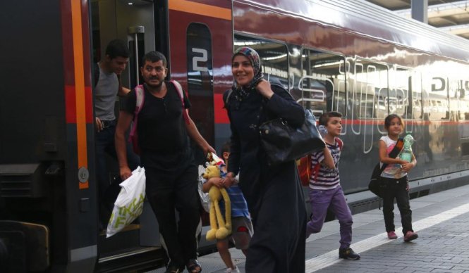 Người tị nạn tươi cười bước ra khỏi chuyến tàu hoả tại Áo - Ảnh: Reuters