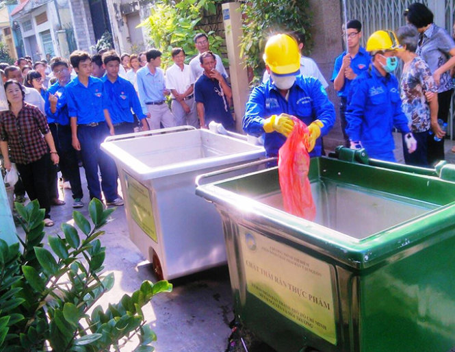 Nhân viên đi thu gom rác thải rắn sinh hoạt được người dân phân loại đặt trước cửa nhà - Ảnh: Sơn Bình