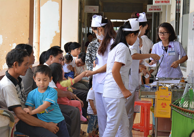 Quá tải bệnh viện, các y bác sĩ tiến hành khám bệnh ngay tại hành lang - Ảnh: Lĩnh Hồng