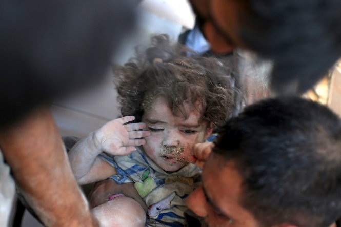 Bé gái Syria được cứu khỏi đống đổ nát do bom ở Douma, gần thủ đô Damascus, ngày 22-8. Phe đối lập nói rằng máy bay quân đội chính phủ đã thực hiện vụ ném bom này  Ảnh: Reuters