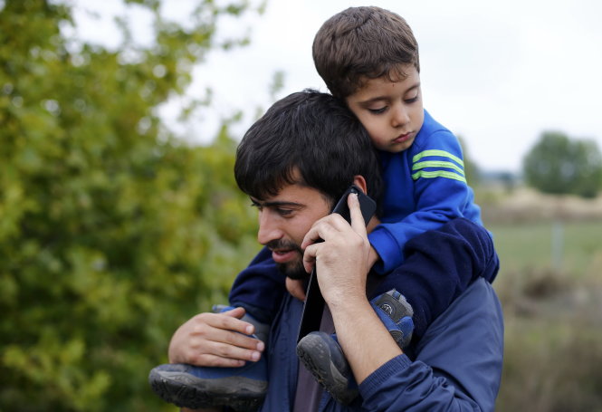 Người nhập cư nói chuyện điện thoại ở Nickelsdorf, Áo khi chờ tìm đường sang Đức - Ảnh: Reuters