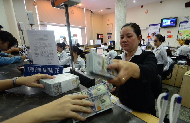 Người dân giao dịch đổi ngoại tệ tại Ngân hàng Đông Á chi nhánh TP.HCM - Ảnh: Thanh Tùng