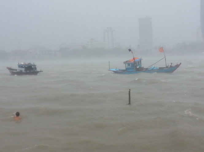 Tàu thuyền neo đậu trên sông Hàn bị sóng nước đánh mạnh, nhiều người dân đang cố gắng kéo vào bờ. Ảnh: PHAN THÀNH